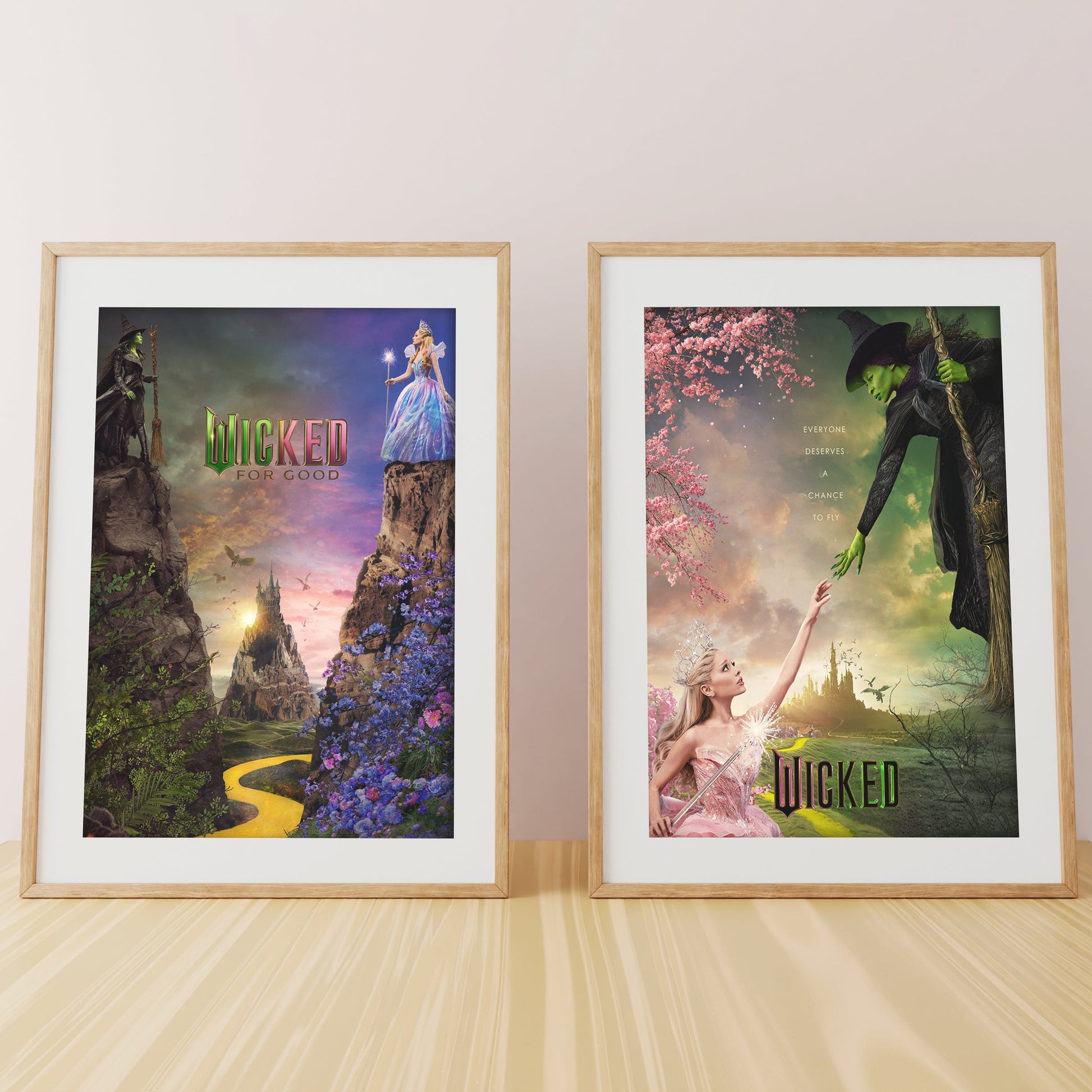 Two framed 'Wicked' theater posters on a wooden surface with a light background