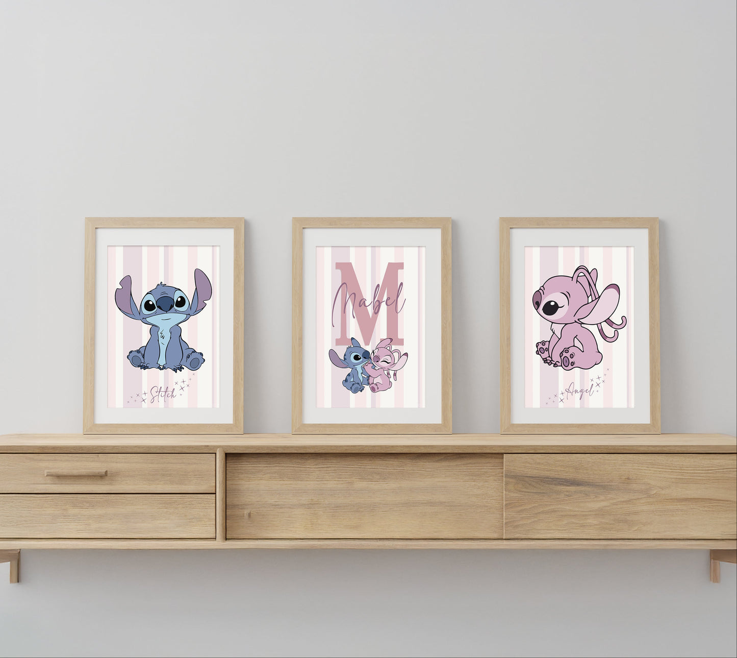 Three framed illustrations of cartoon characters on a wooden shelf against a light gray wall.
