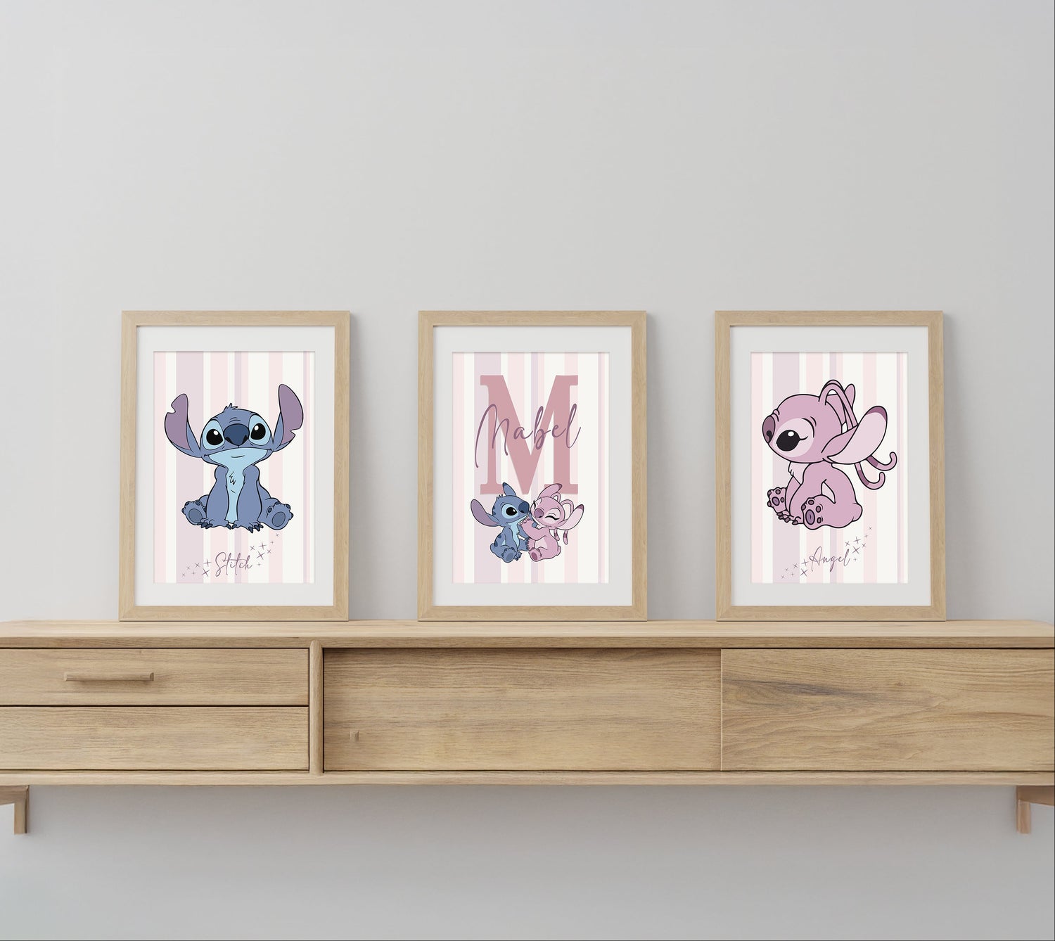 Three framed illustrations of cartoon characters on a wooden shelf against a light gray wall.