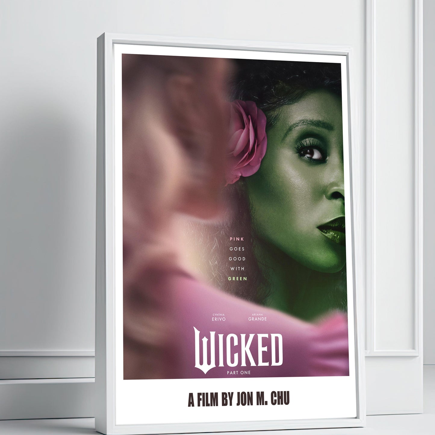 Framed poster of 'Wicked' with a character's face and pink flower on a white wall.
